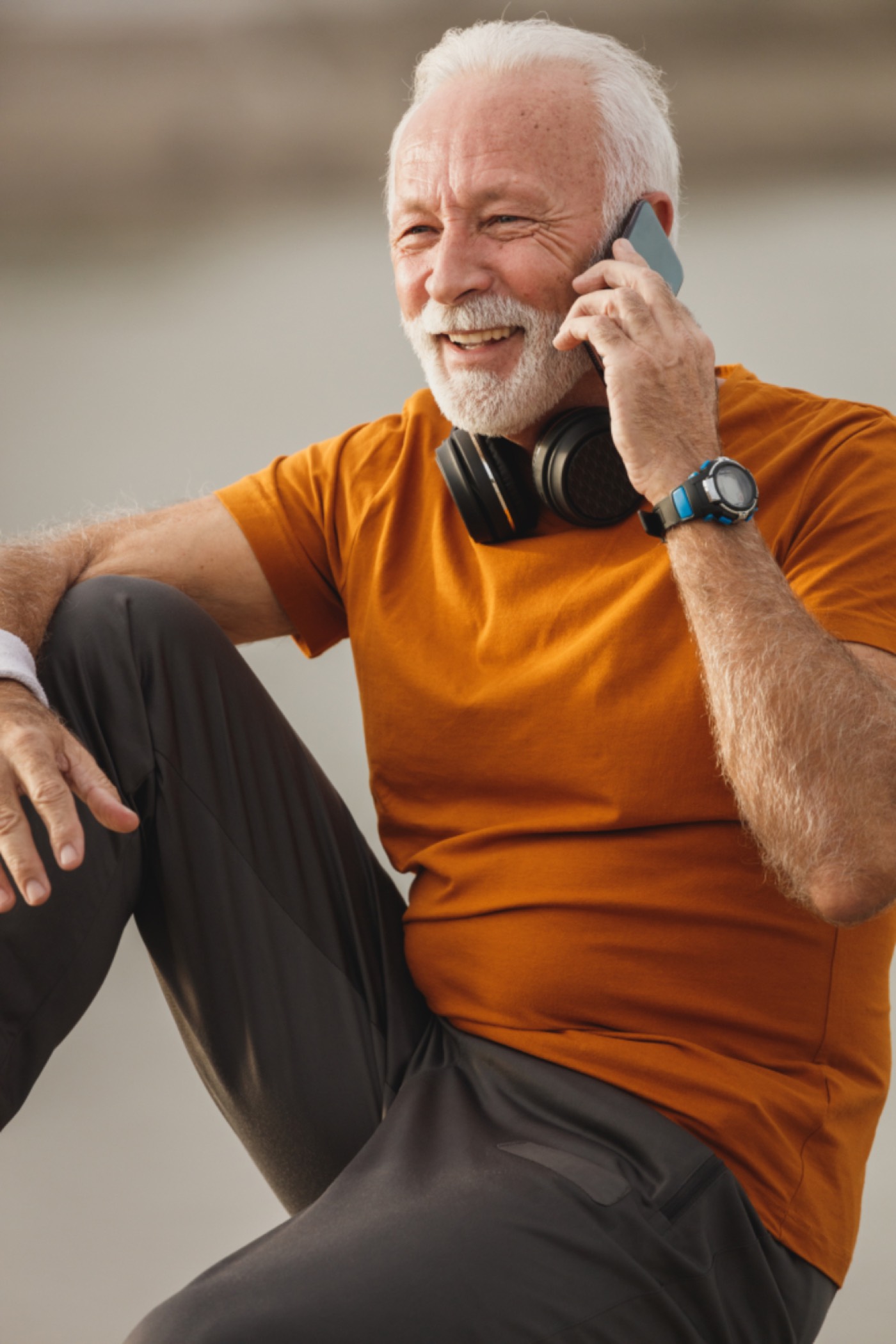 A man with headphones around his neck, phone in hand, mid-sentence.