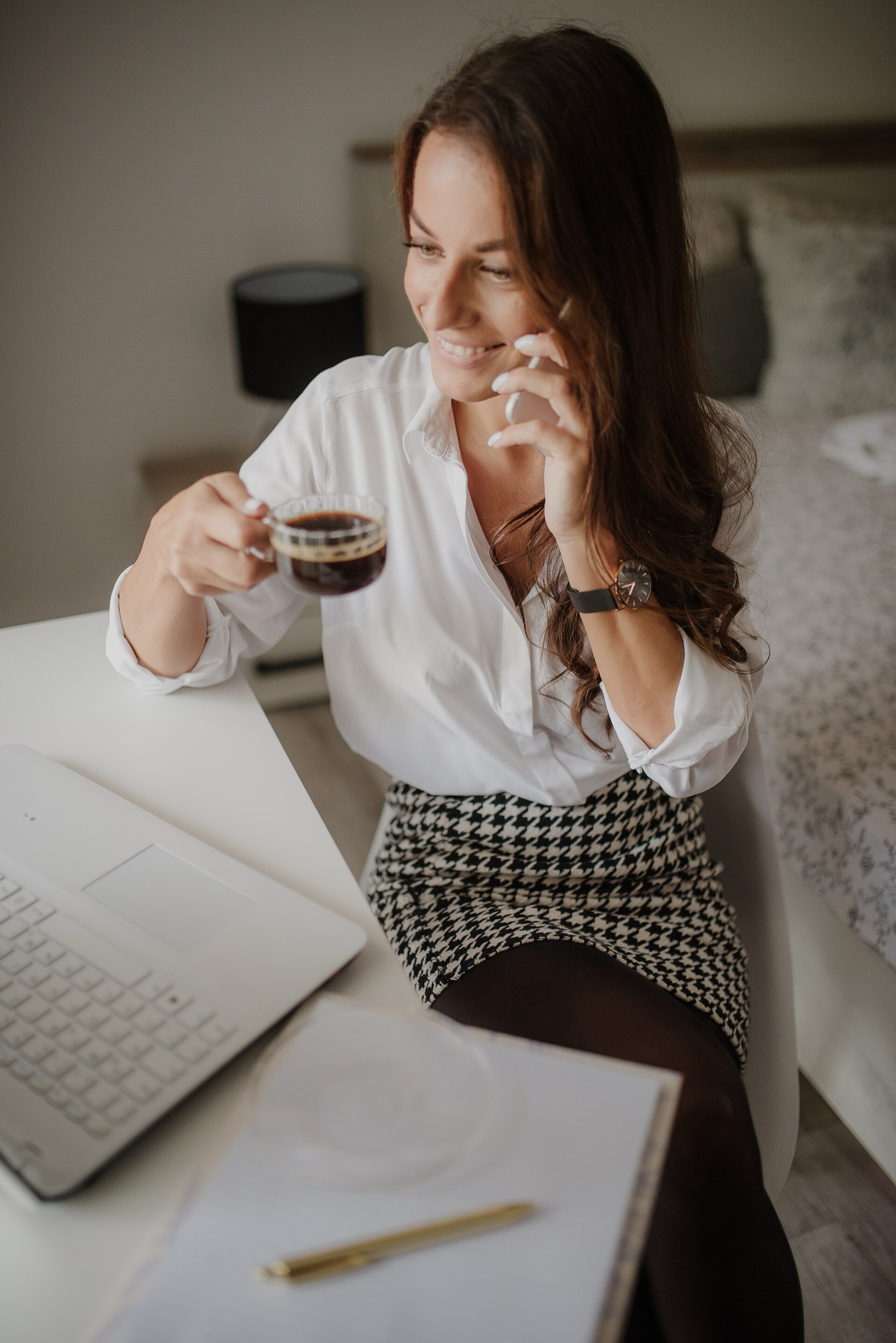 A woman on the phone at her desk, coffee in hand, talking through her week with Disco.